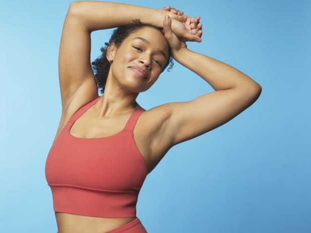 Image of a woman with her arms up showing her under arms. 