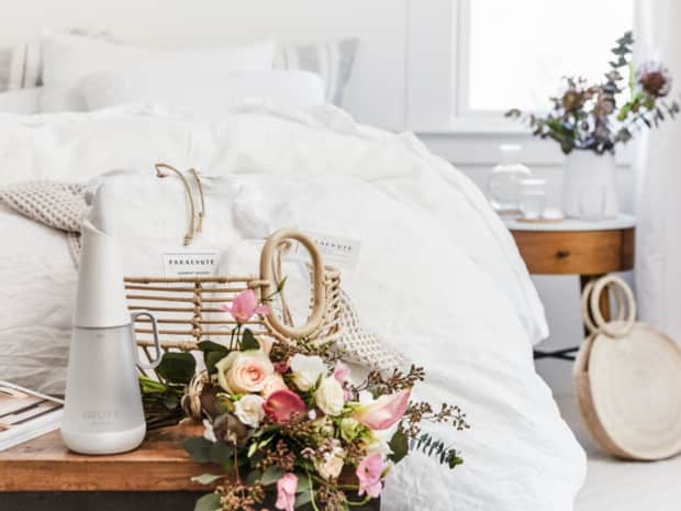Bed with table in front with flowers and Grove products