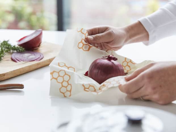 Person wrapping onion in bee's wax wrap
