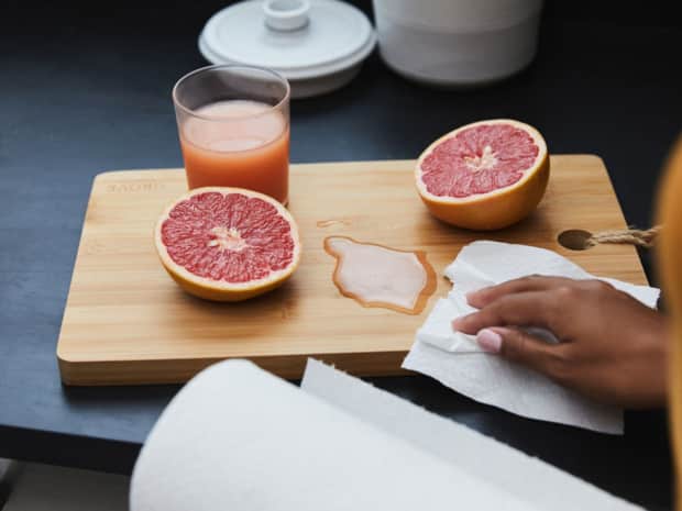 Image of a grape fruit next to a cup of juice and paper towel. 
