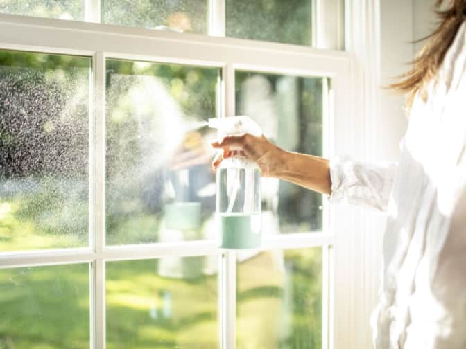 Woman spraying cleaner onto window