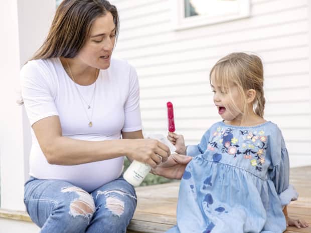 Woman spraying stain remover on daughter's dress