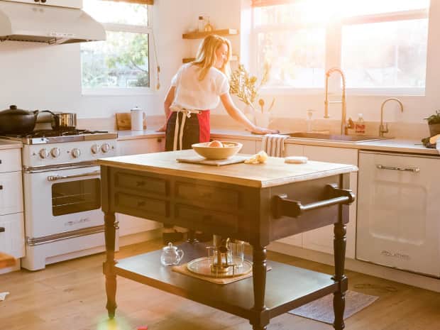 blonde haired women cleaning kitchen countertops in late afternoon