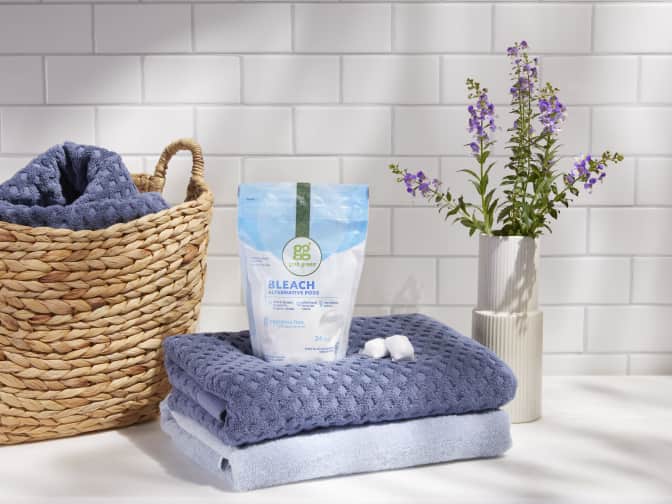 Photo of Grab Green Bleach Alternative on stack of bath towels next to basket