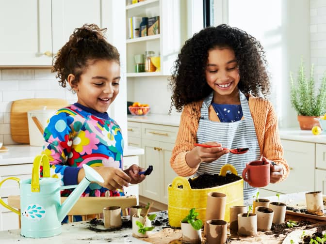 Two girls making a seedling garden on the kitchen countertop with recycled paper towel and toilet paper cardboard.